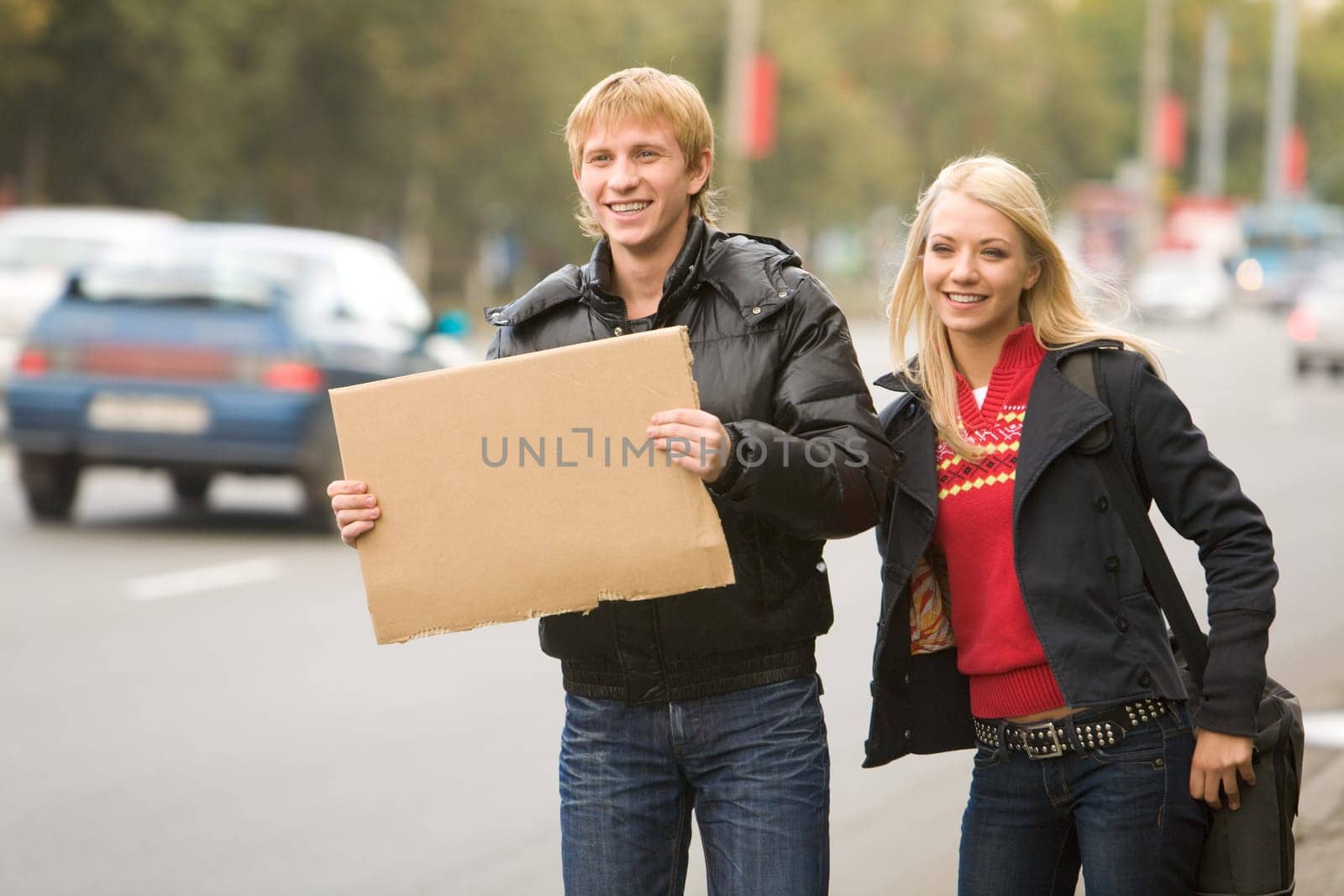 Photo of pretty girl and handsome guy hitchhiking on city road