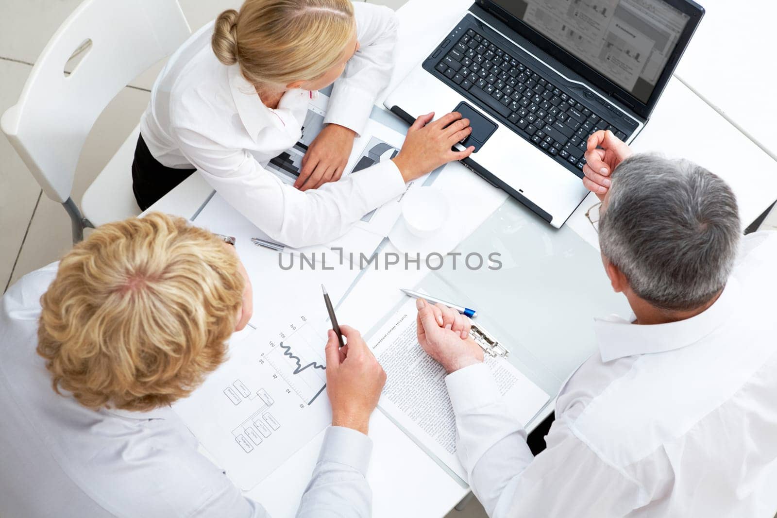 Above view of workteam discussing computer project at meeting