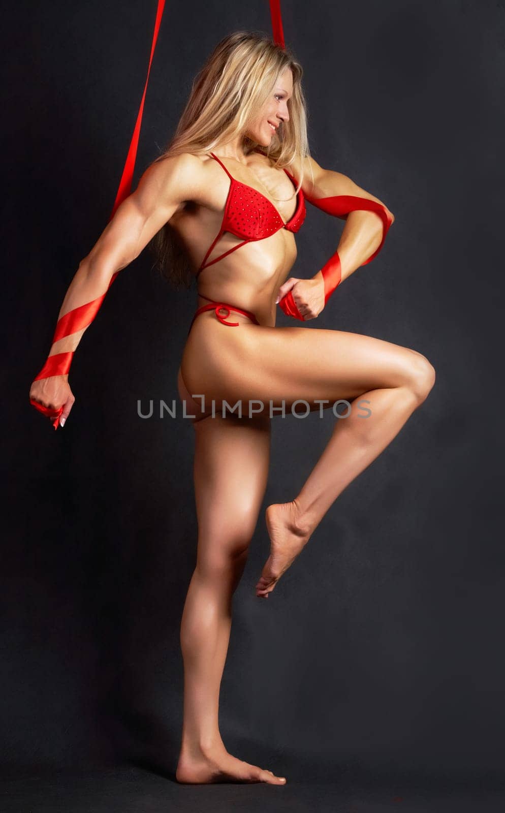 A beautiful model in red bikini marching to the right with red ribbons wound round her arms