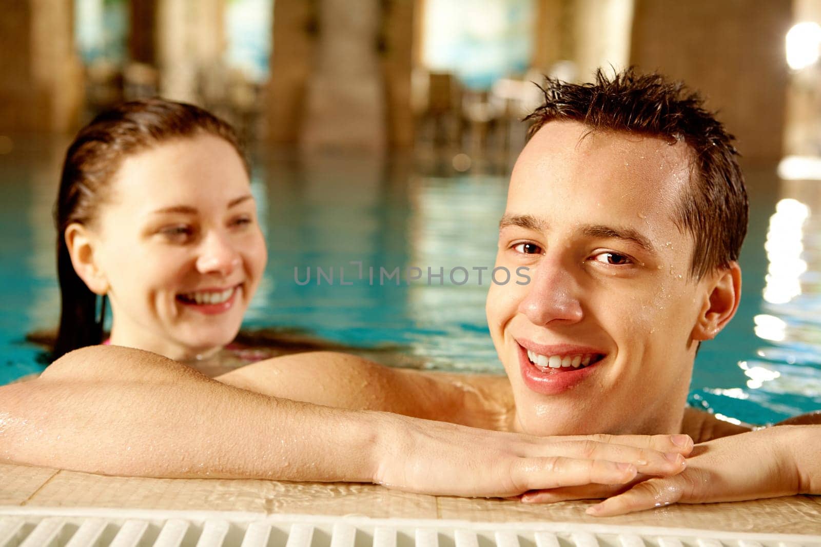 Portrait of happy man with pretty girl on background in swimming pool