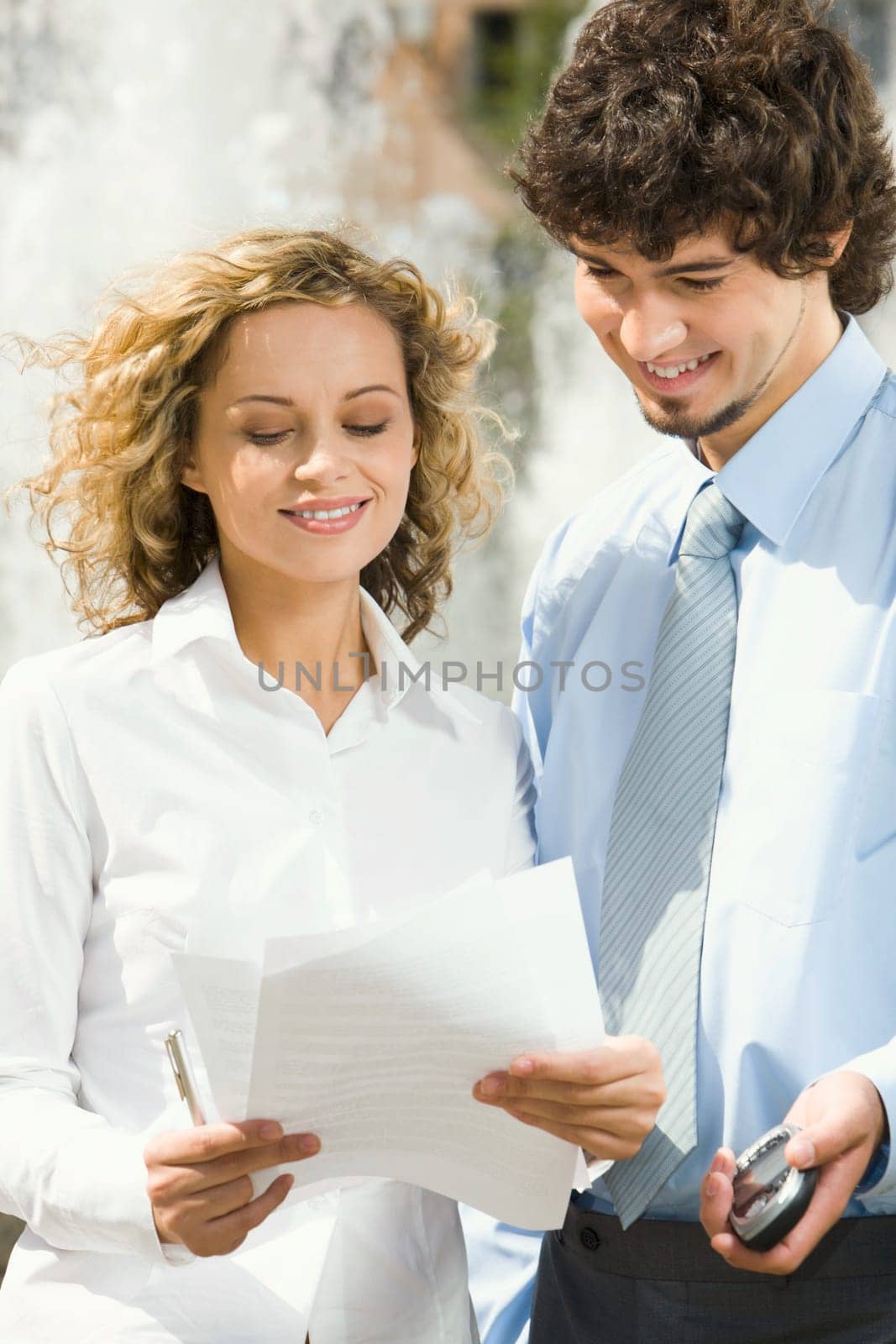 Portrait of two businesswomen  standing outside ahead of the fountain reading the contract
