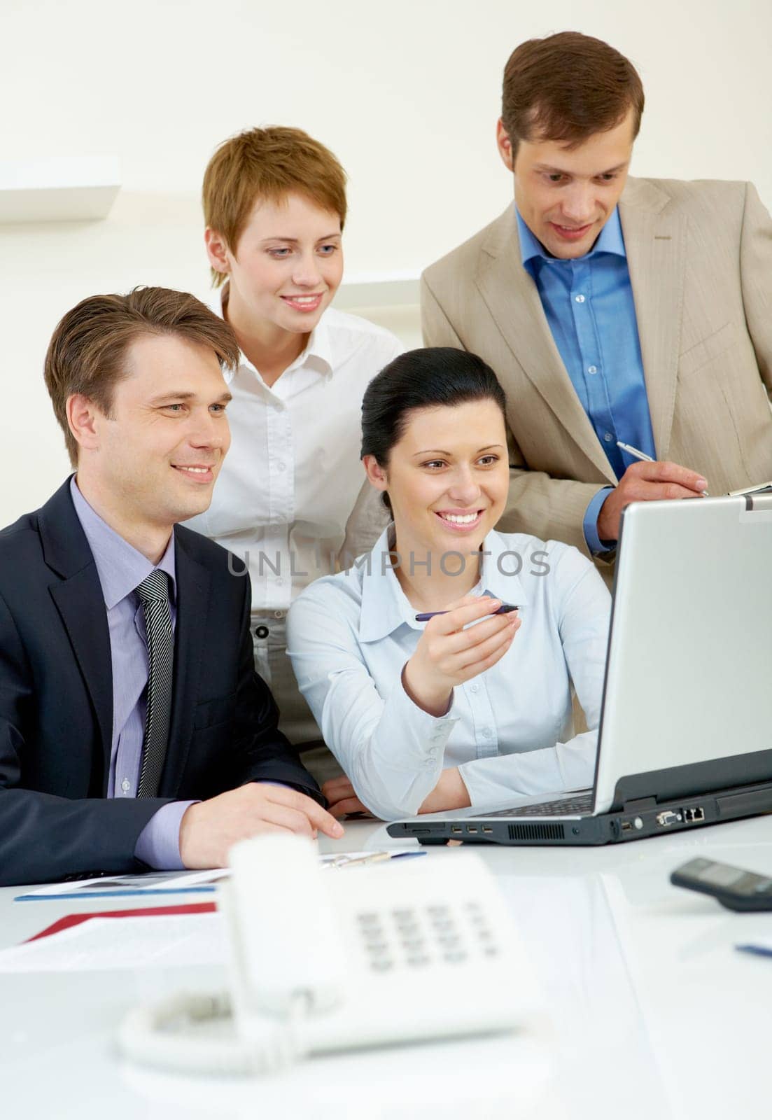 Portrait of business group looking at laptop screen in office