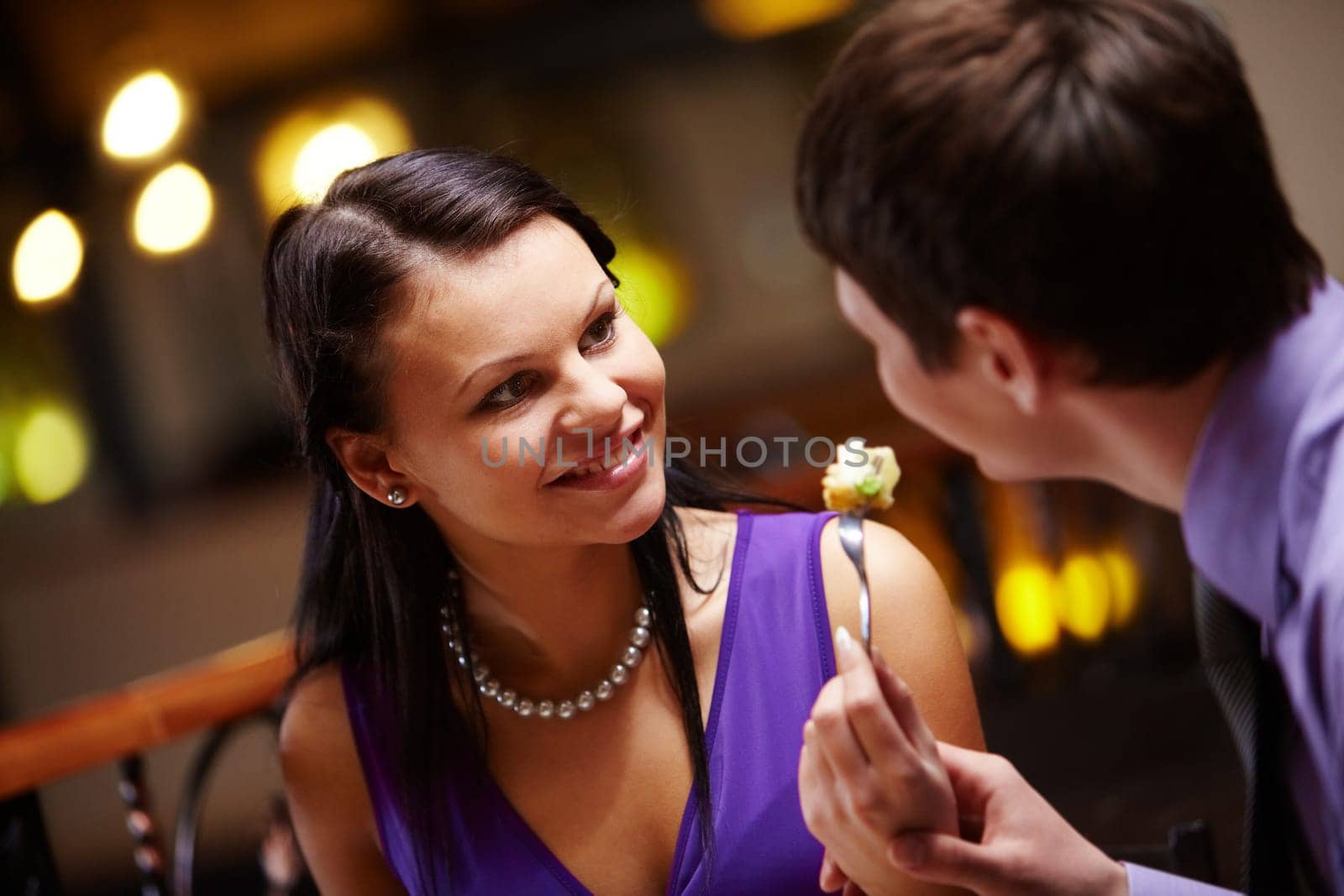Portrait of woman looking at man and holding fork with food