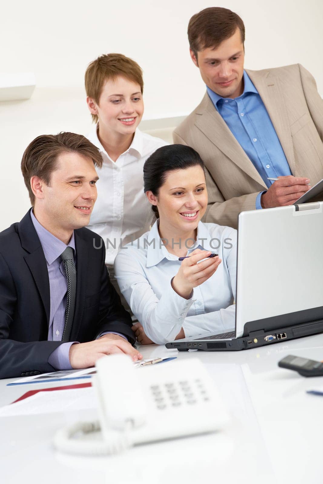 Portrait of business group looking at laptop screen in office