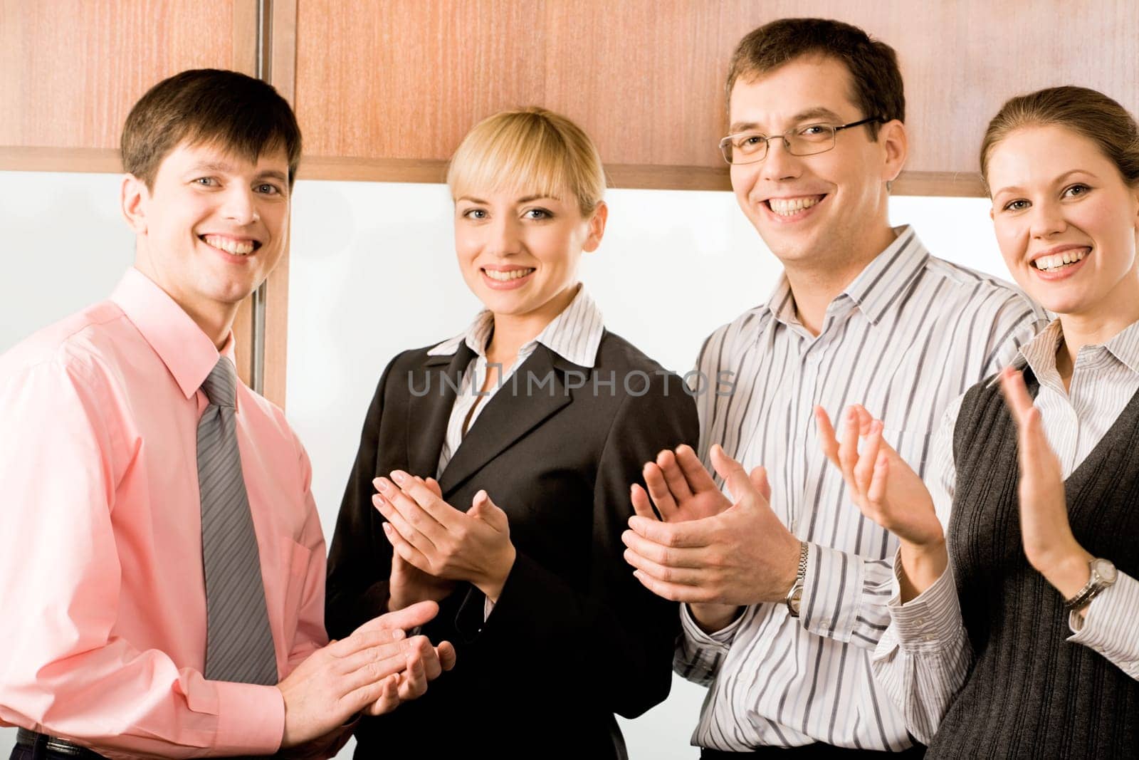 Portrait of four business people smiling and applauding in the office