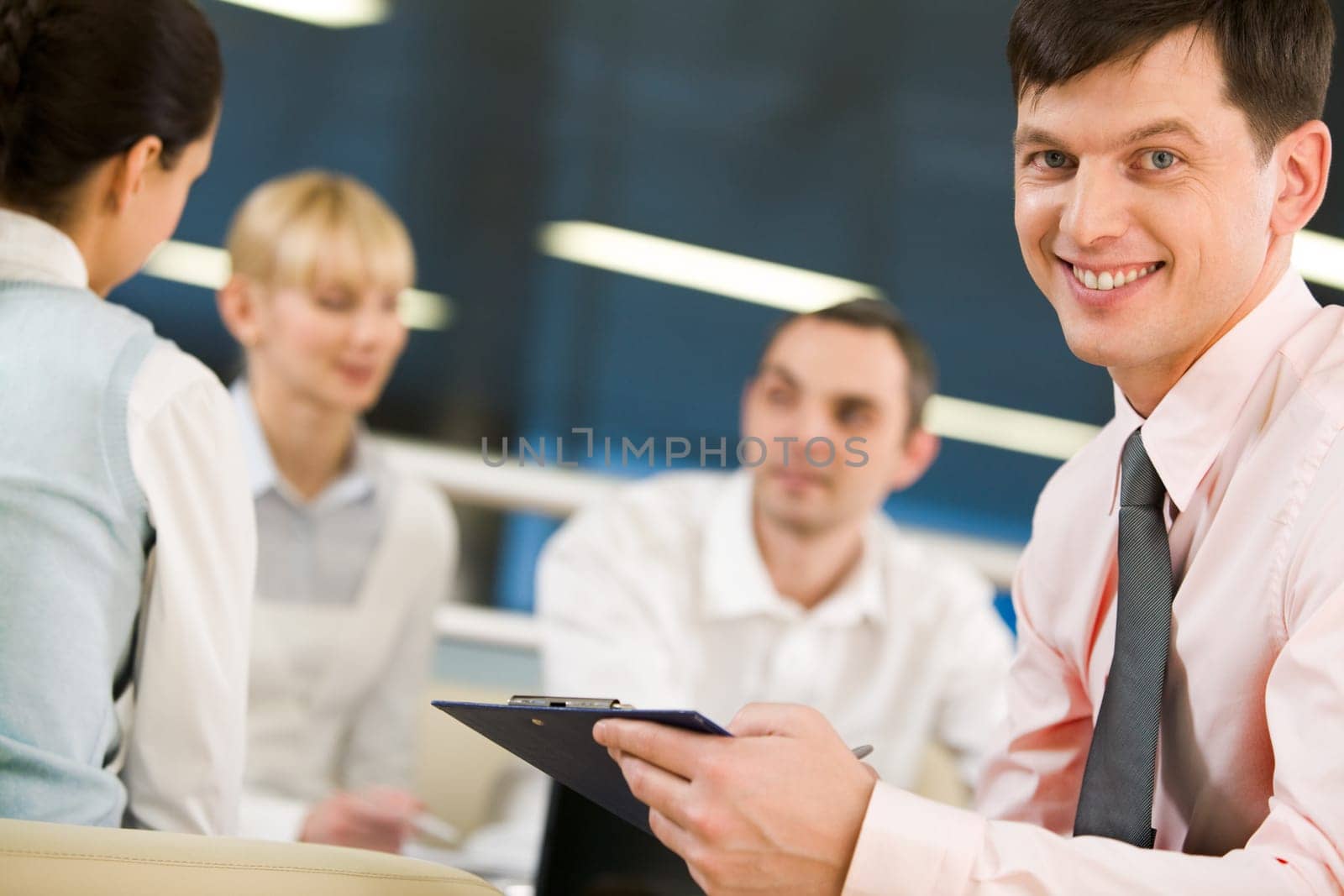 Portrait of happy businessman smiling at camera on background of working employees