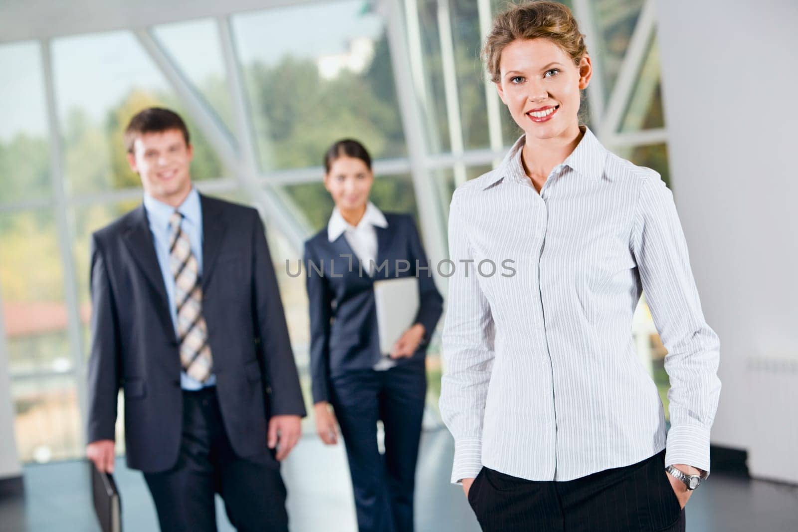 Successful woman putting her hands into the pocket on the background of  business people