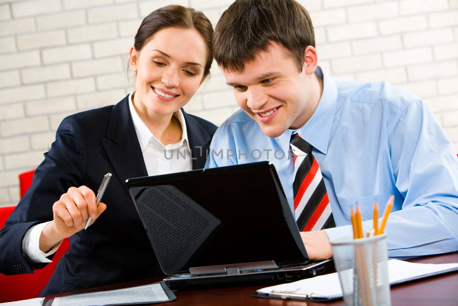 Business man and woman sitting at the table and looking at the laptop