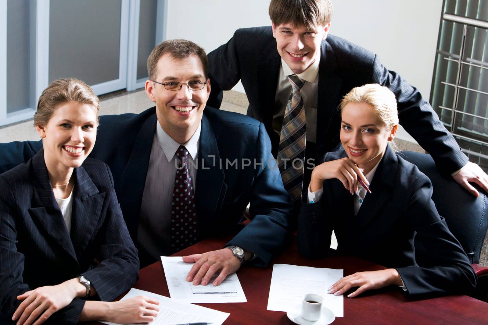 Large group of young businessmen looking at camera gathered together around the table
