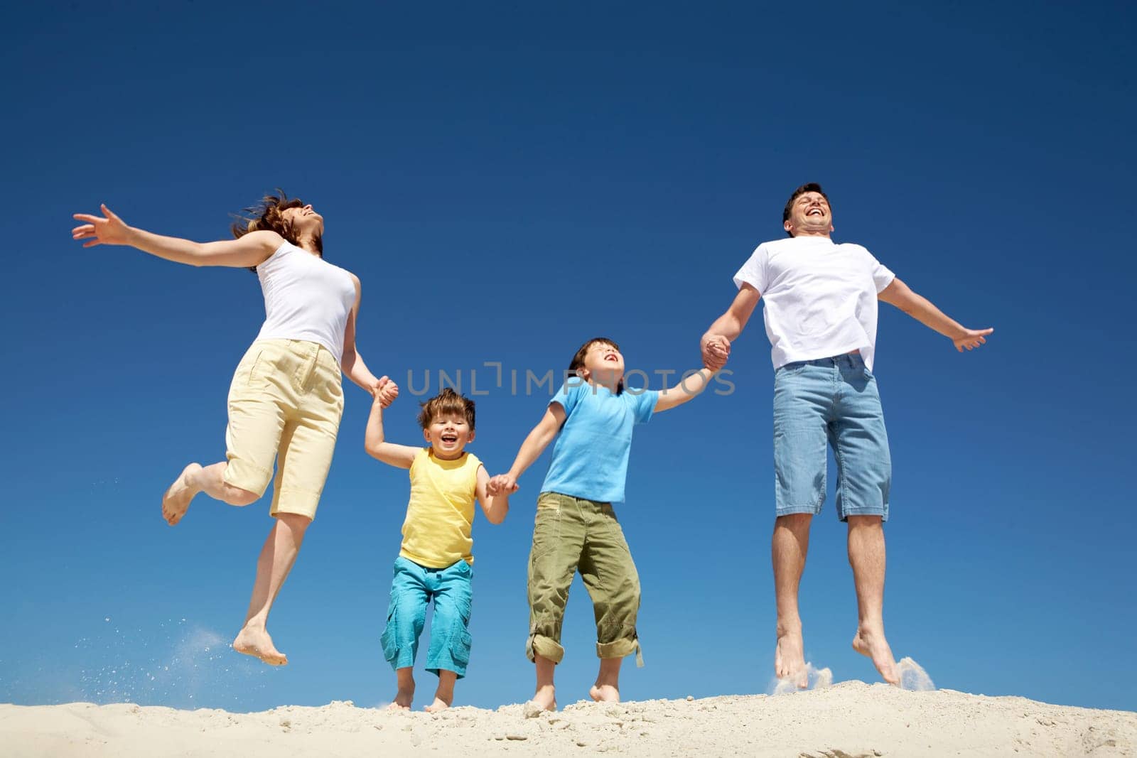 Photo of happy parents holding their son by hands in jump with bright blue sky at background