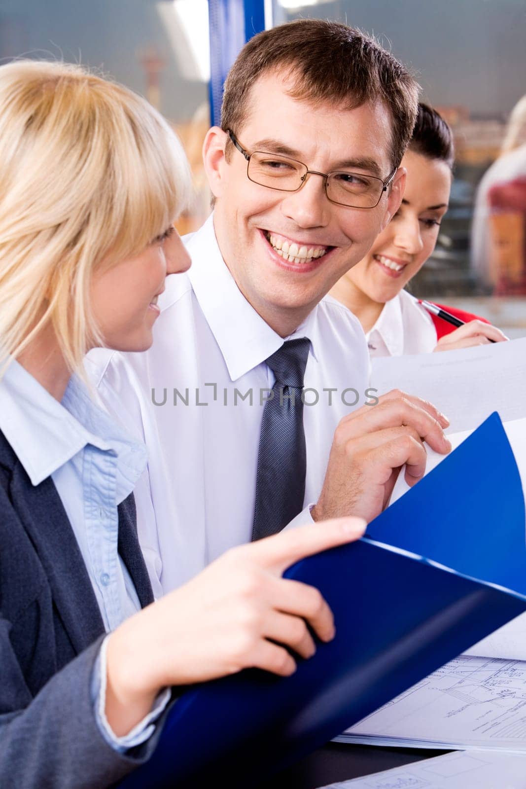 A business leader looking at one of the business ladies giving her a big smile with the other business lady at the background