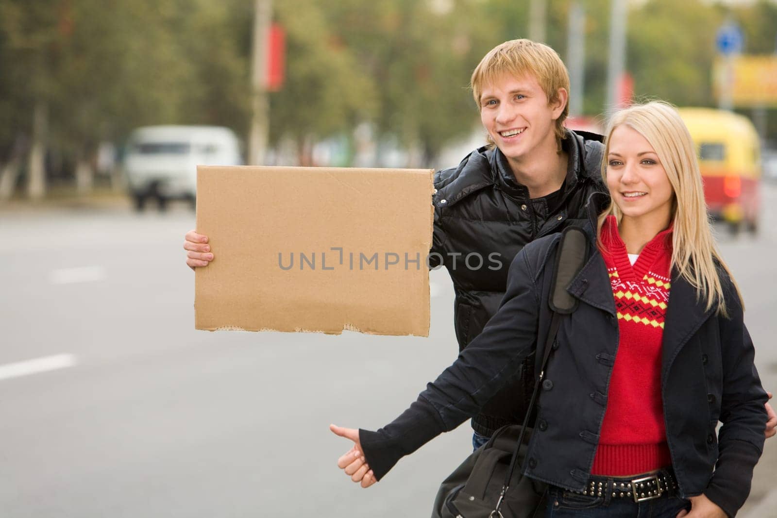Photo of pretty girl and handsome guy hitchhiking on city road