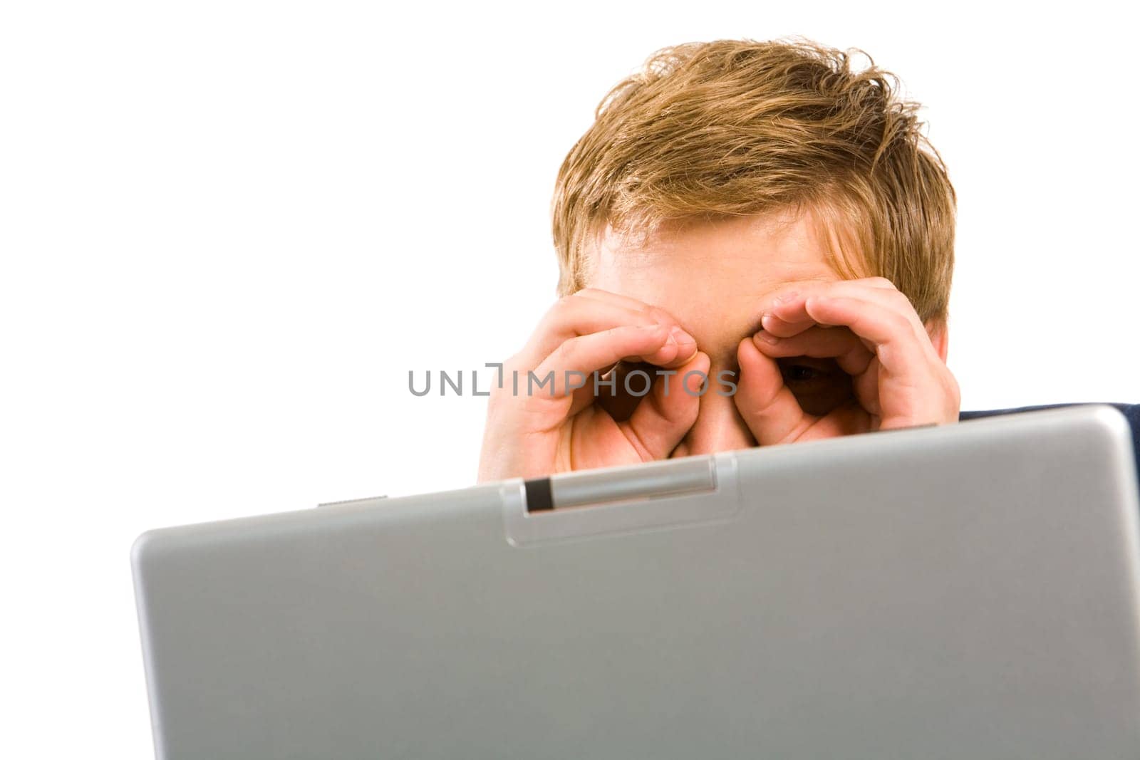 Portrait of businessman with his hands by eyes while sitting in front of laptop