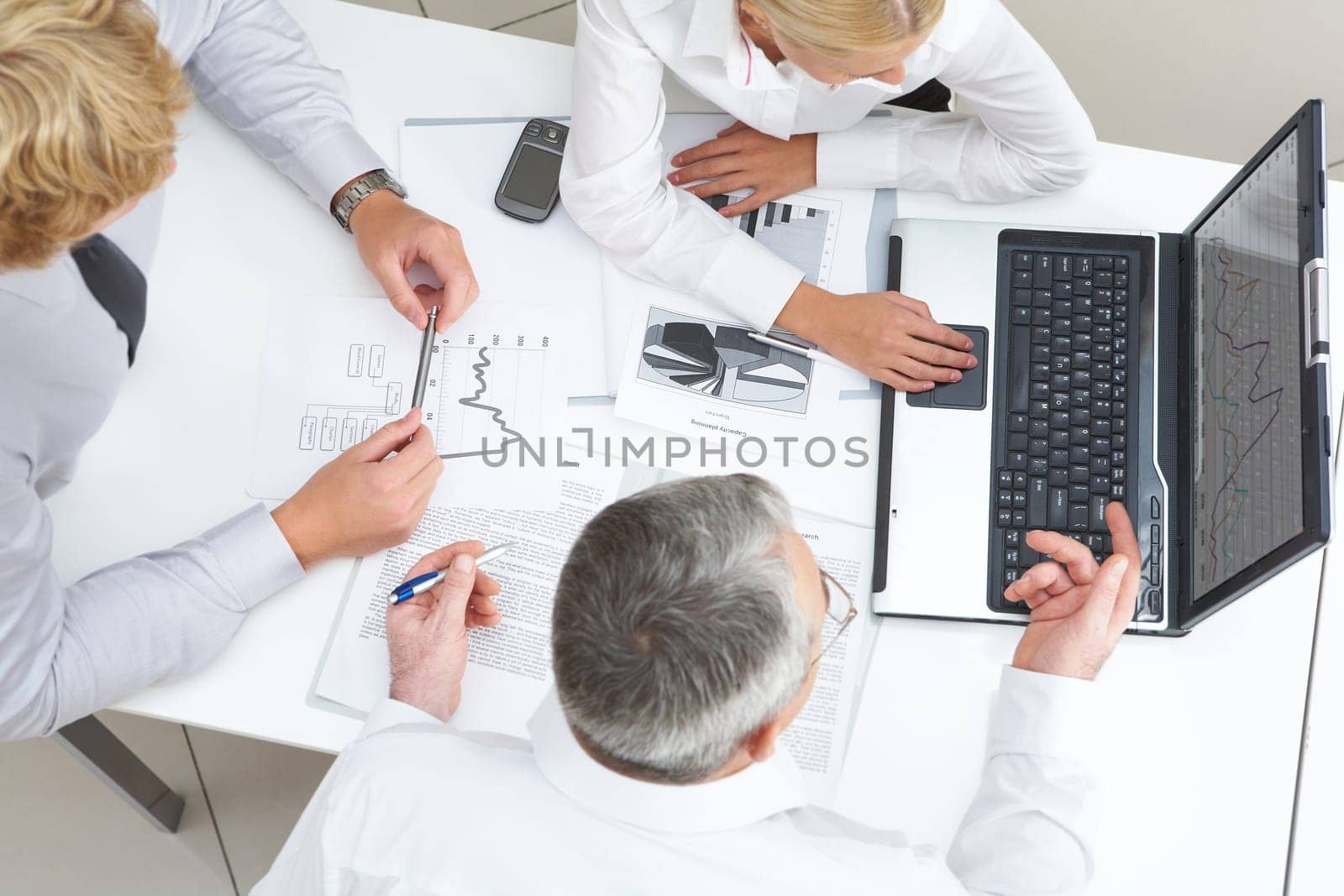 Above view of workteam discussing computer project at meeting