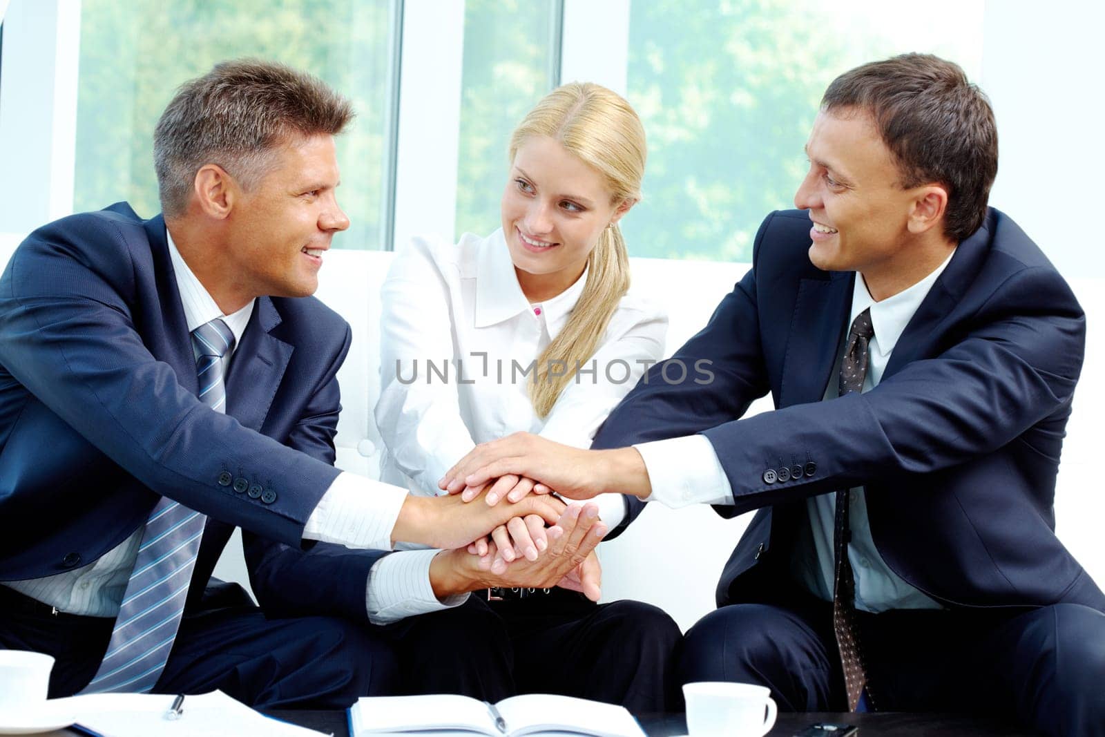 Portrait of smiling co-workers making pile of hands and looking at each other