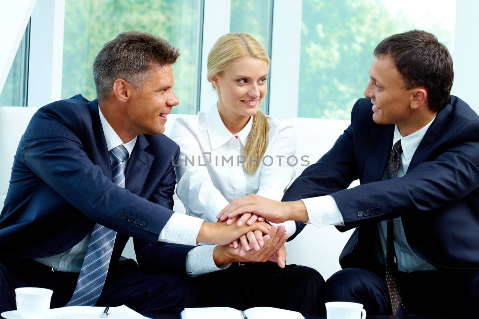 Portrait of smiling co-workers making pile of hands and looking at each other