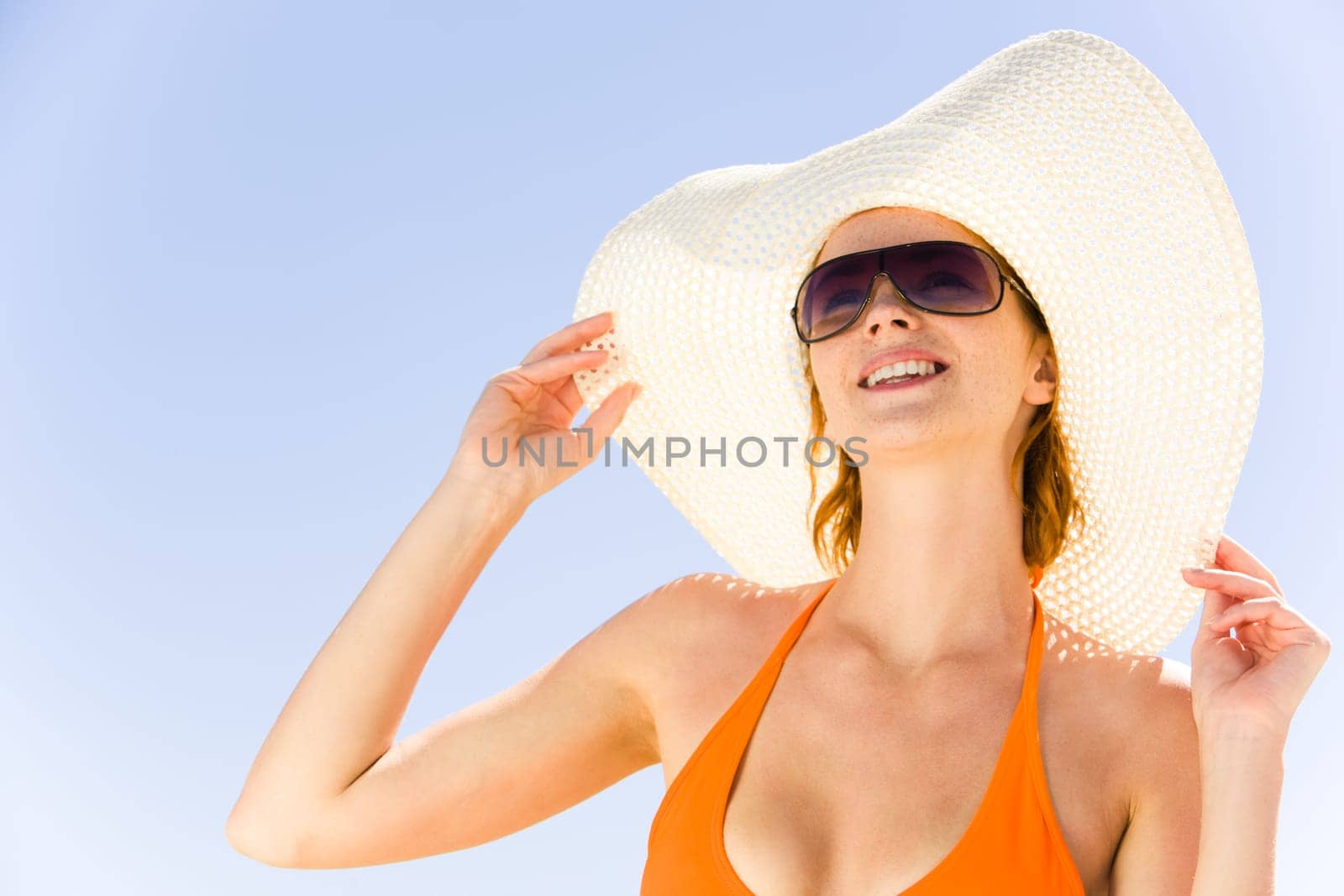 Close-up of pretty girl in hat and sunglasses on the background of blue sky