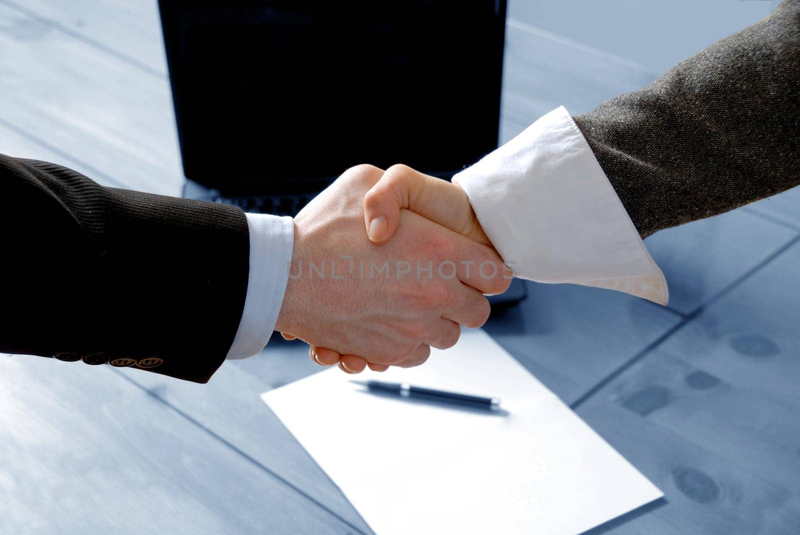 man and woman shaking hands in front of laptop