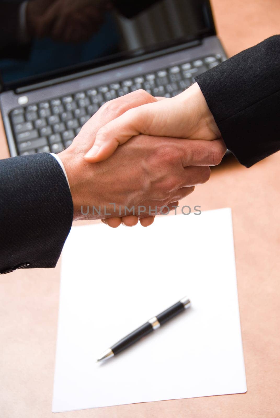 2 hands shaking with a blank contract and pen