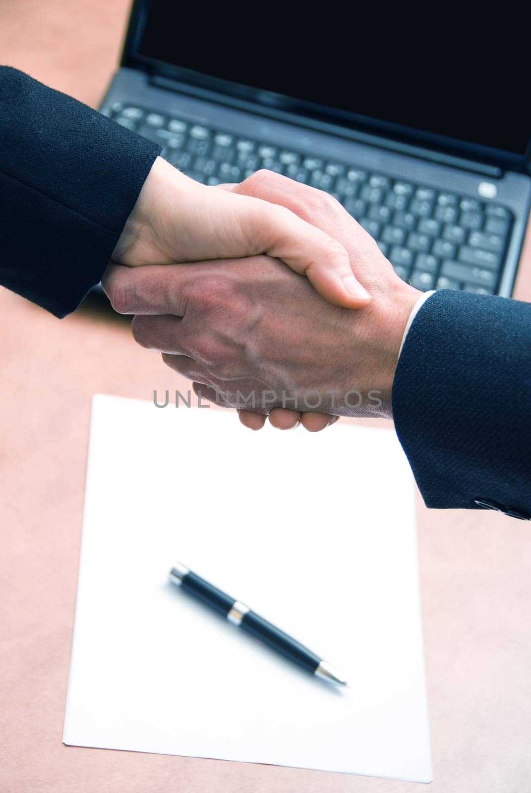 2 hands shaking with a blank contract and pen