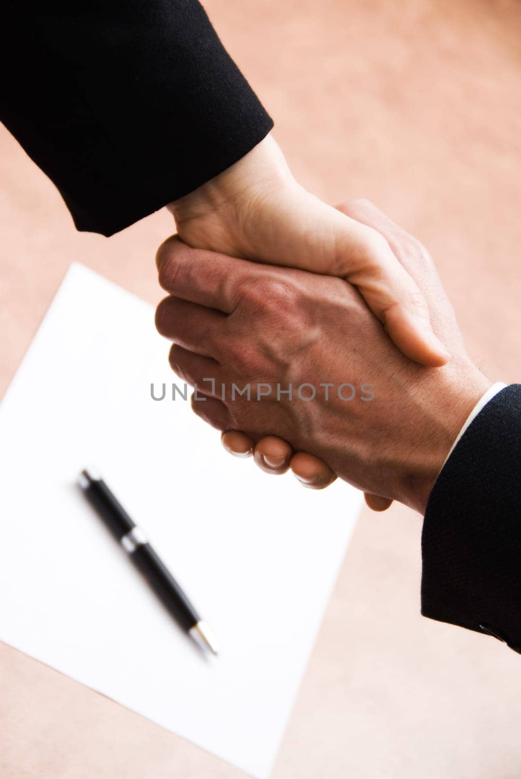 2 hands shaking with a blank contract and pen