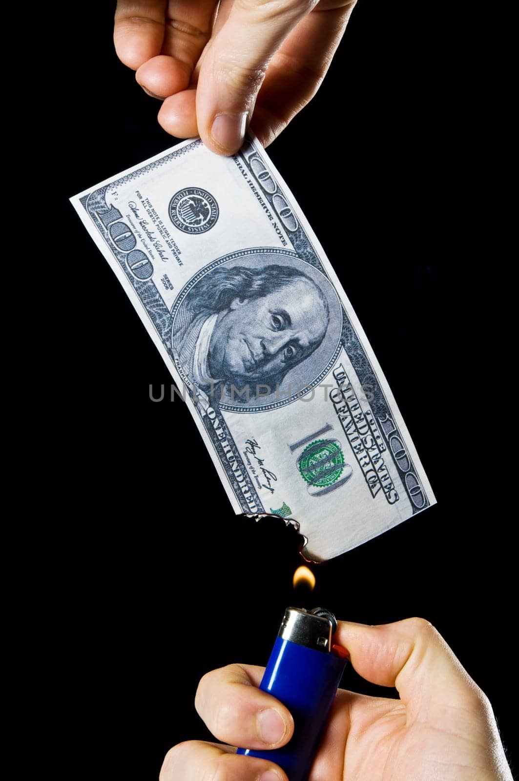 putting fire to a us banknote on black background