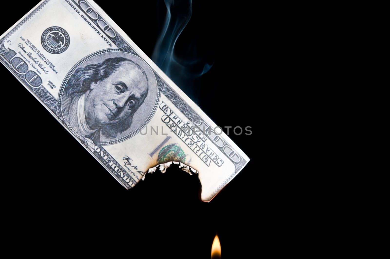 putting fire to a us banknote on black background