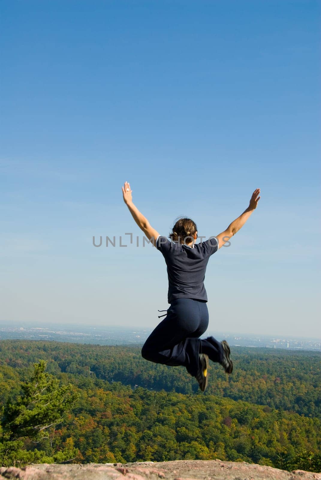 Woman on the top of a mountain happy jumping