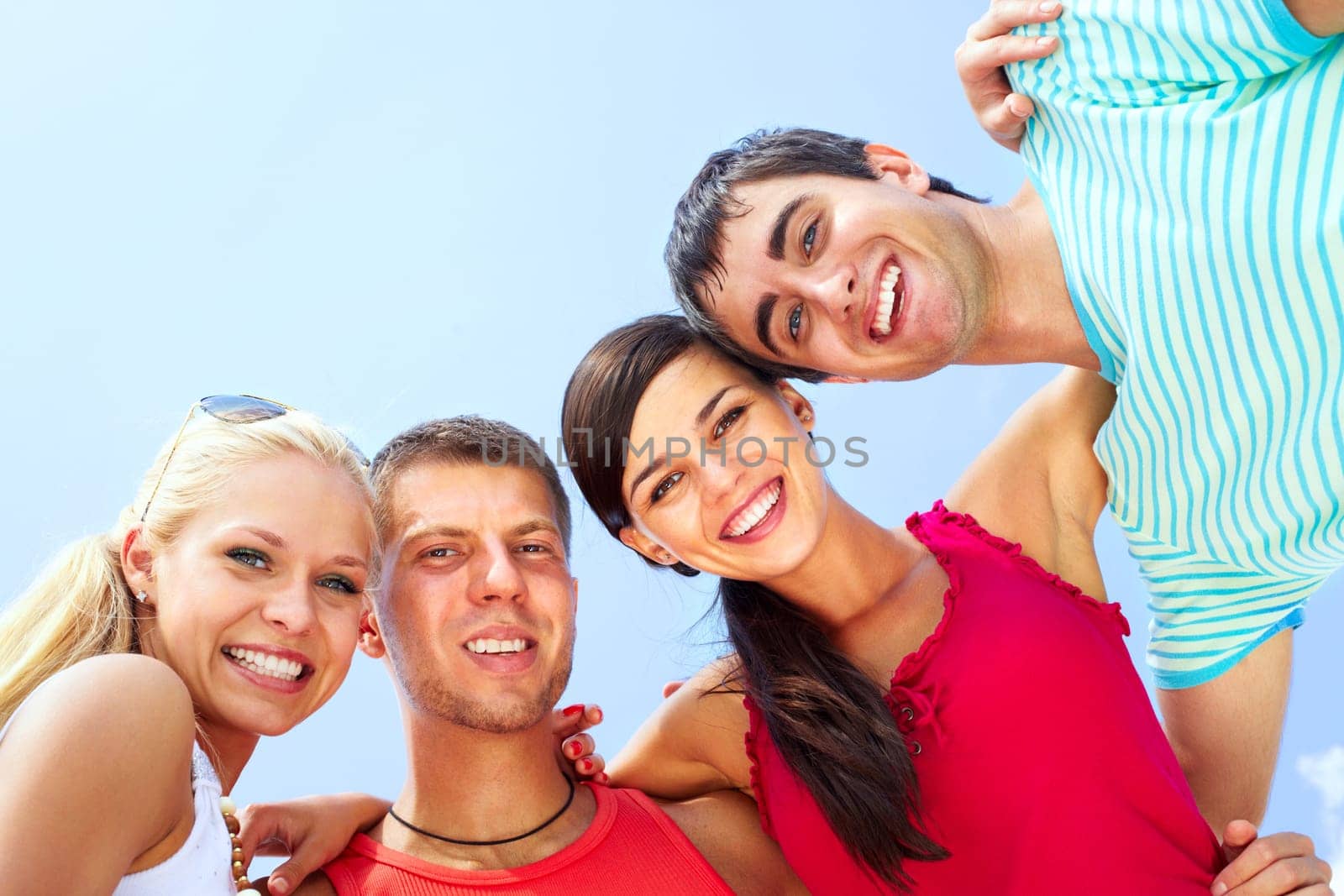 Portrait of four hugging friends looking at camera and smiling