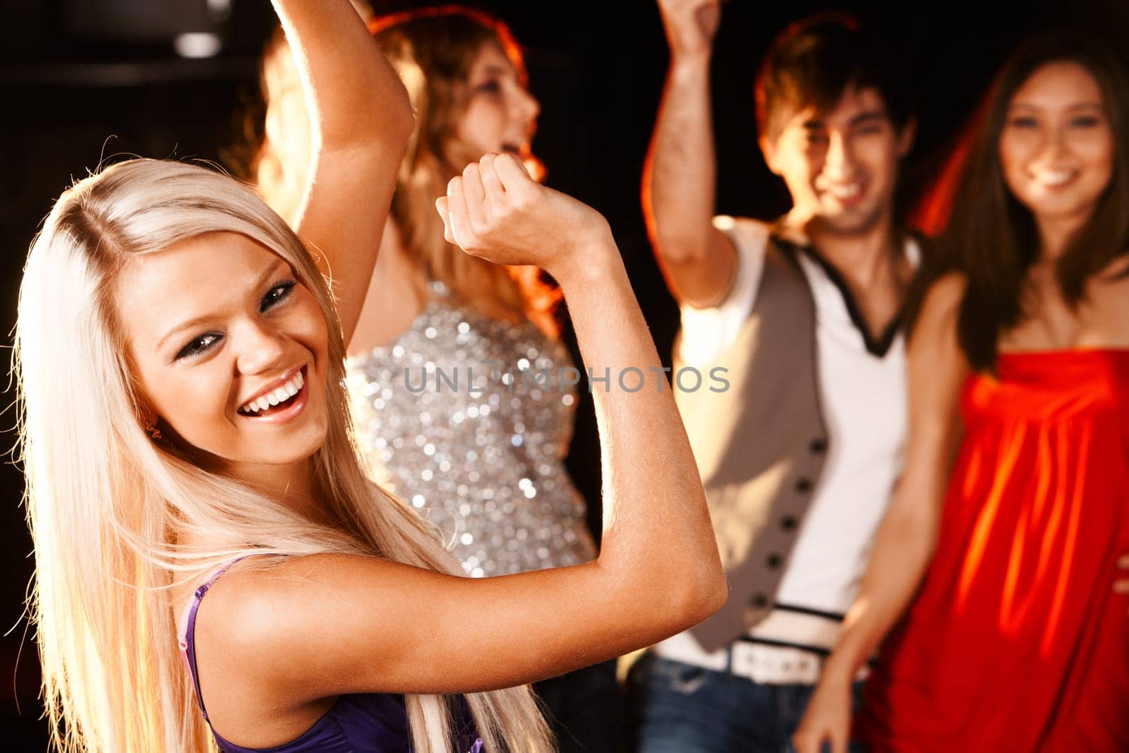 Portrait of cheerful girl dancing at party with her friends behind