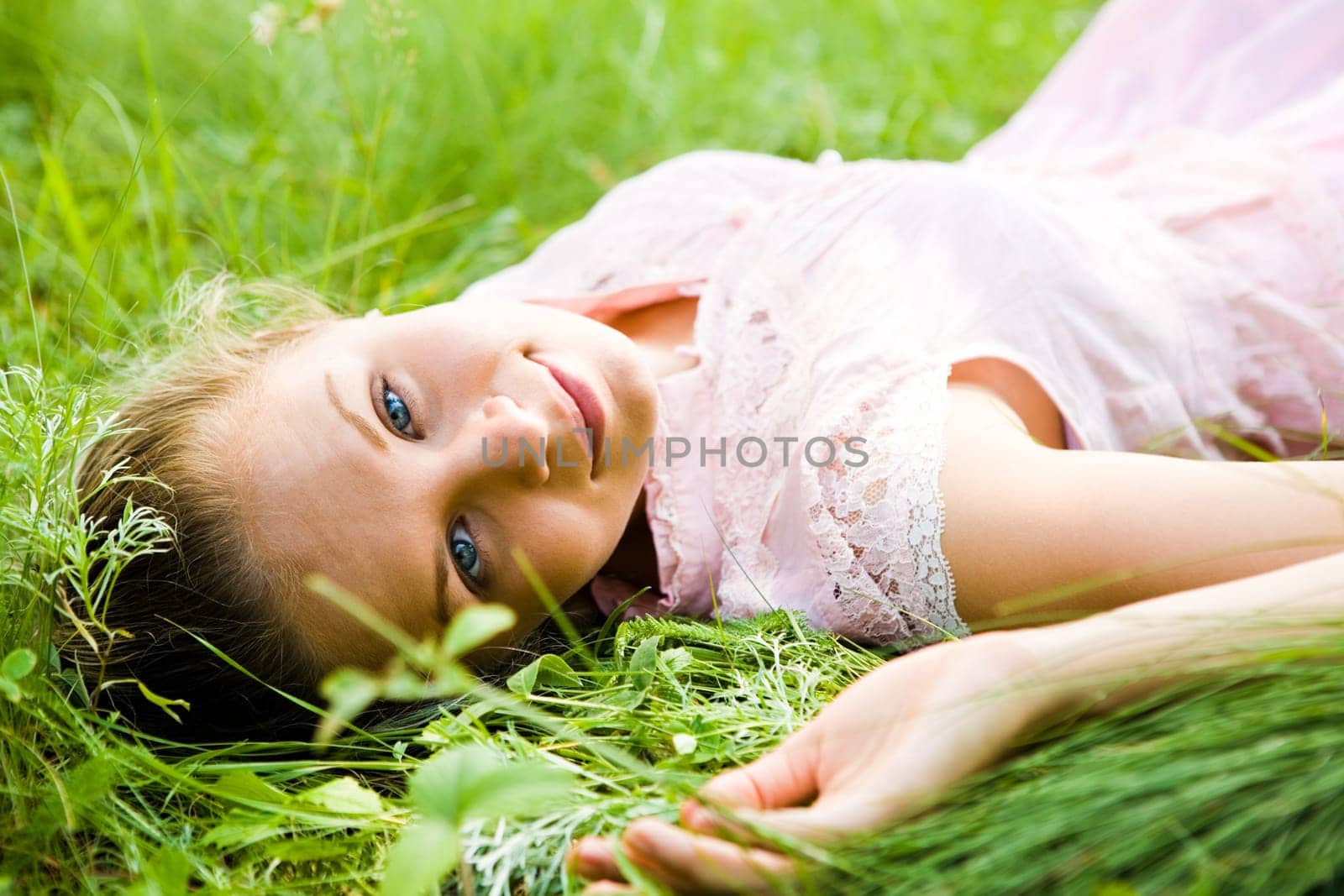 Close-up of young female lying on fresh grass and looking at camera during rest