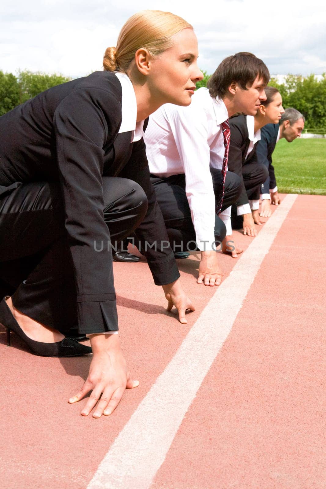 Image of businesswoman looking attentively forwards waiting for signal to run with partners on background