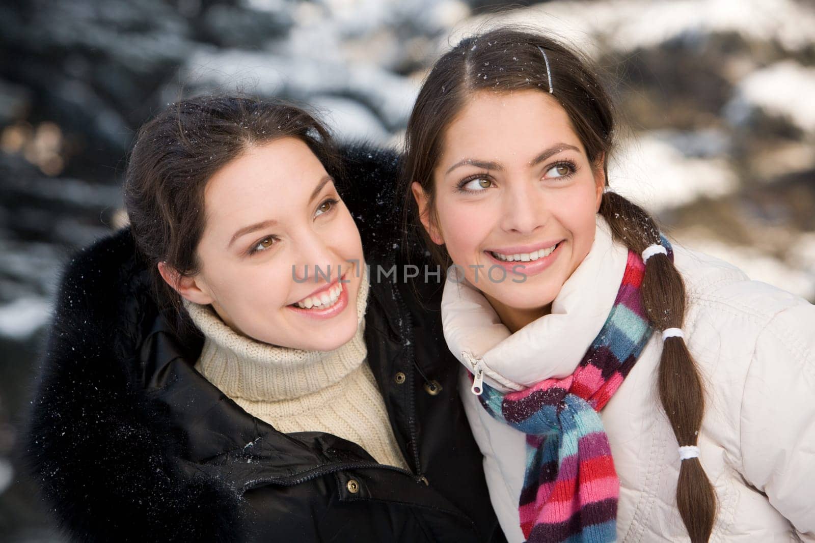 Two smiling girls having fun in the winter forest