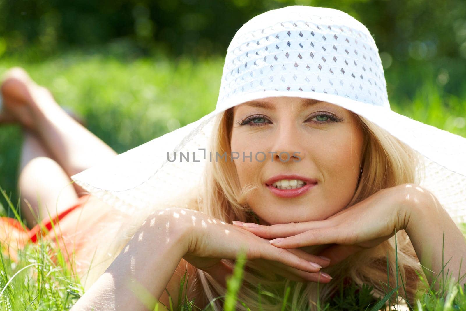 Pretty young lady in elegant hat relaxing in green grass