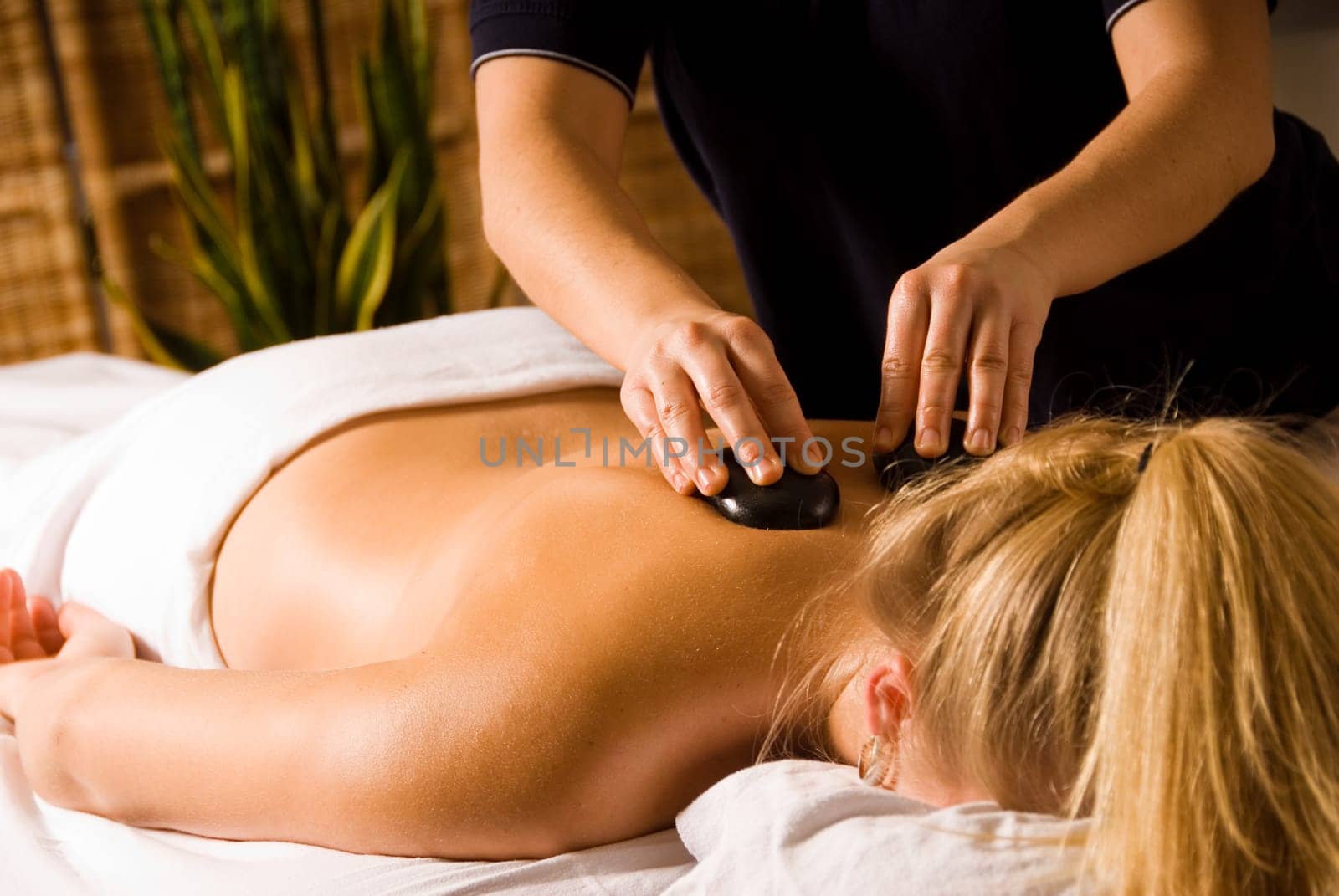 therapist giving a hot stone massage to woman