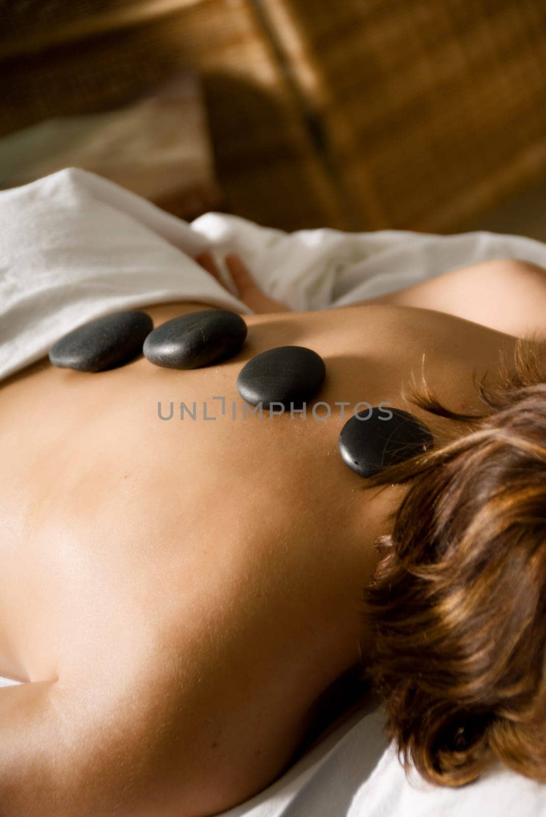 woman in a day spa with hot stones on her back