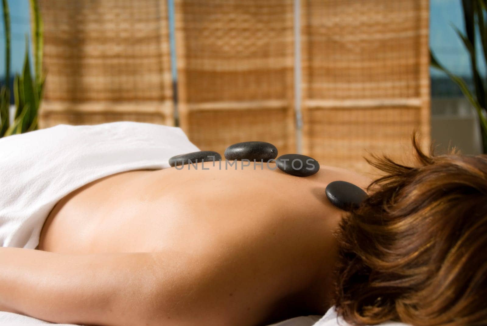 woman in a day spa with hot stones on her back