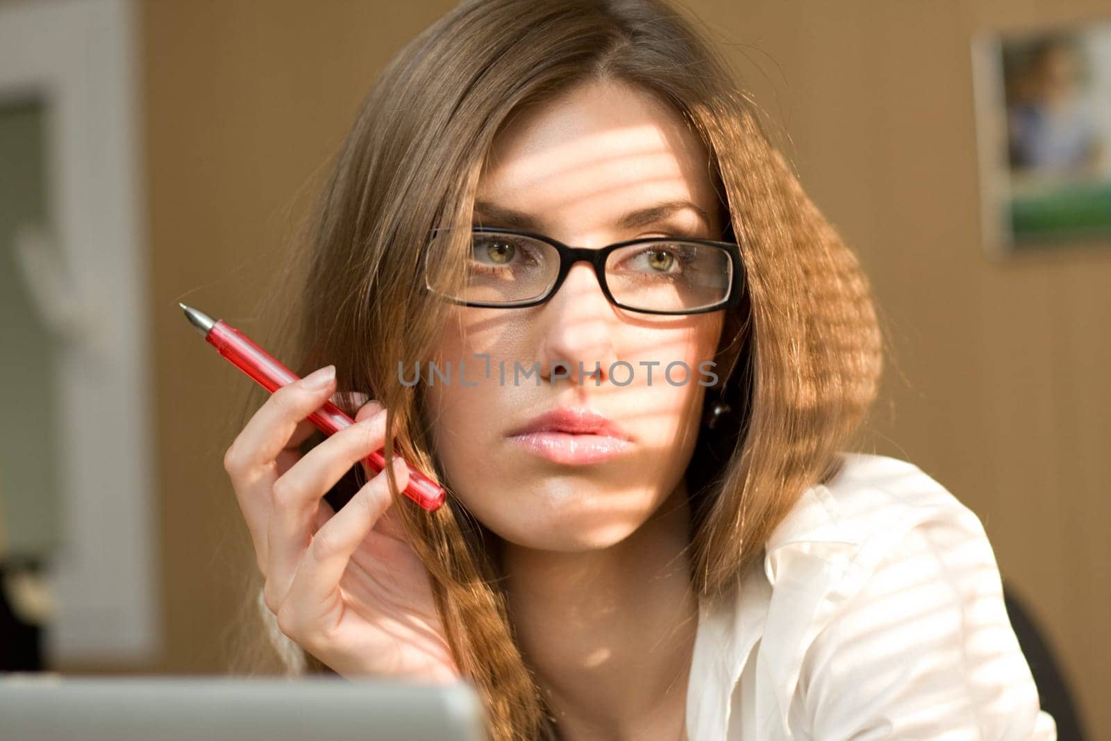 Close-up of serious woman with pen in hand and pensive expression