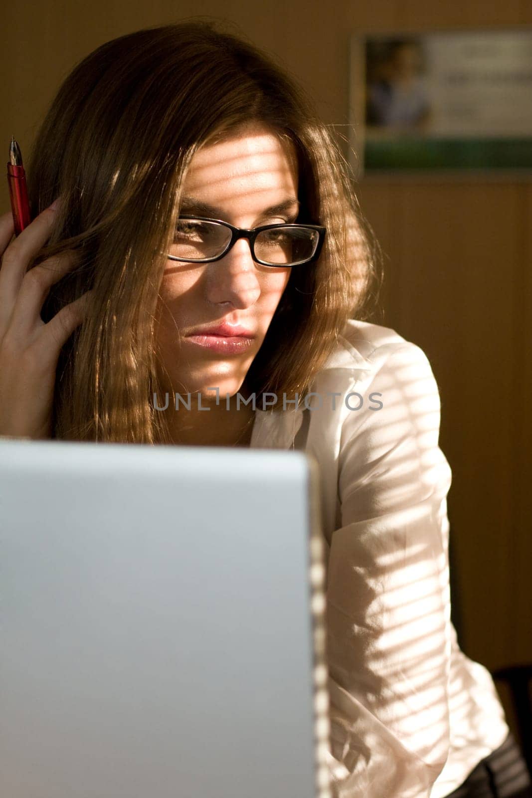 Photo of thinking woman in eyeglasses with laptop near by