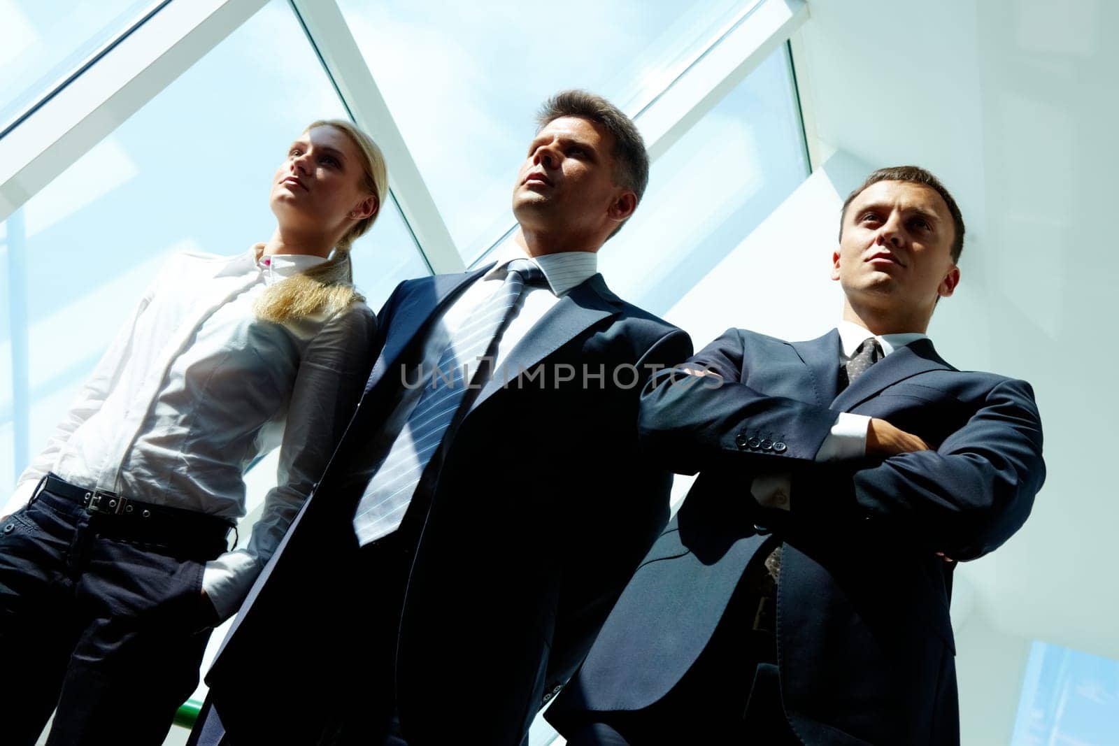 Row of three smart employees looking forwards indoor
