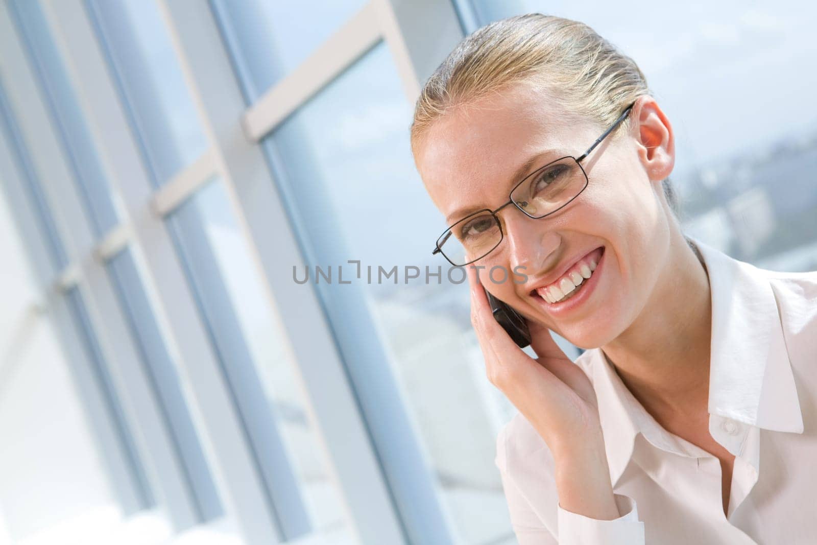 Portrait of pretty business woman talking by mobile phone and looking at camera with smile