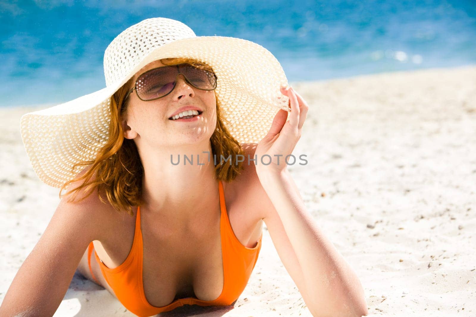Portrait of happy woman lying on the seashore and sunbathing