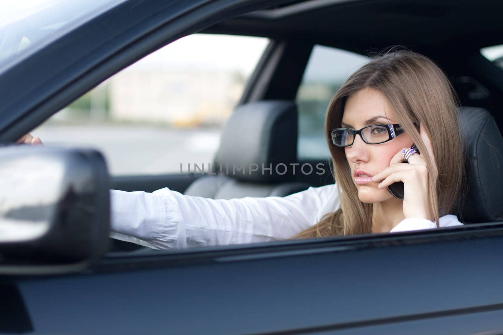 Image of busy woman calling on cellular phone while sitting in her car