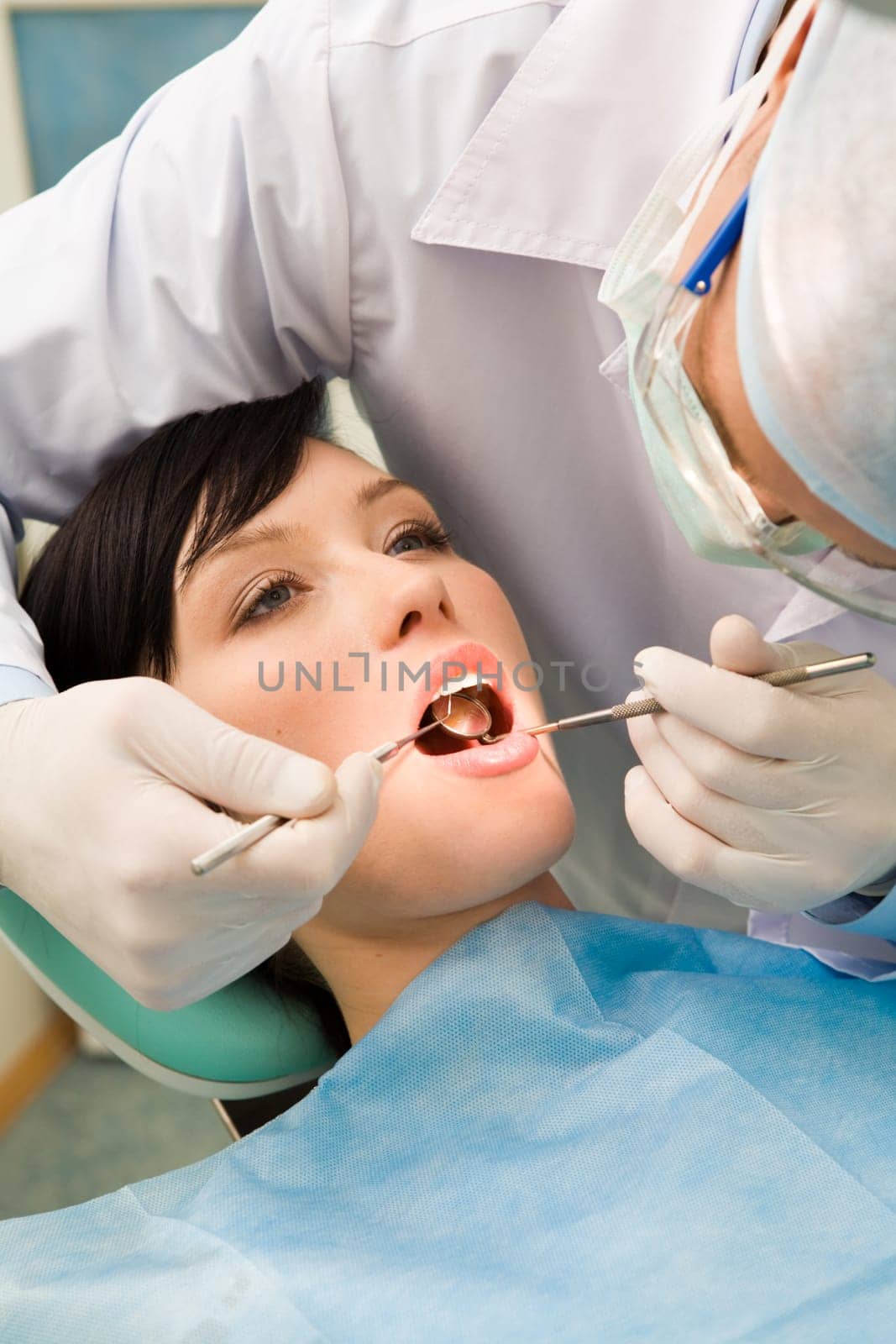 Image of young lady with dentist over her checking oral cavity