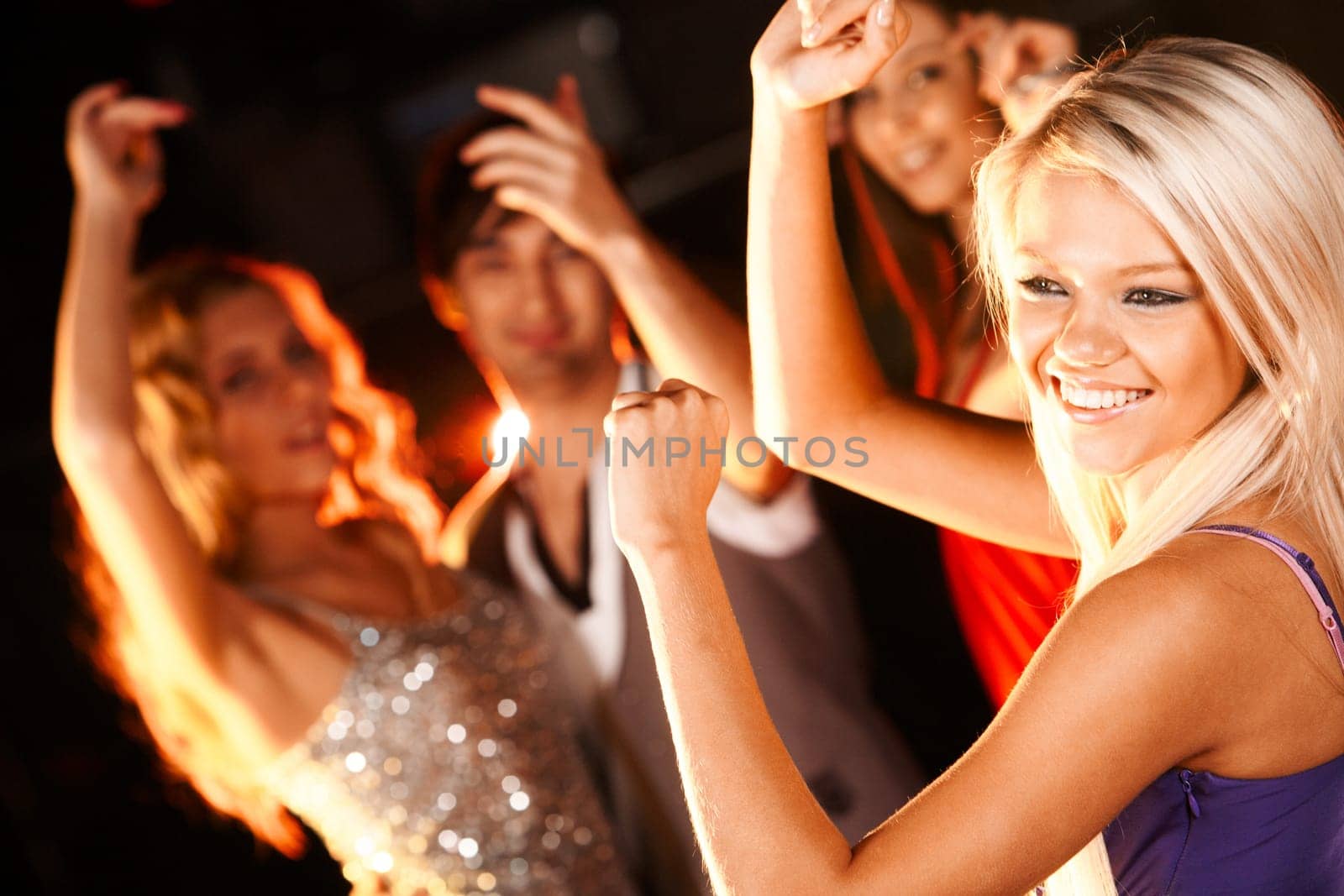Portrait of cheerful girl dancing at party with her friends behind