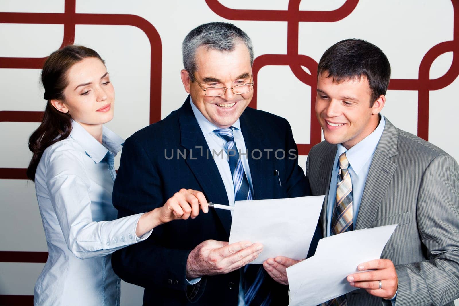 Portrait of happy businessmen looking into document at which elegant lady pointing during meeting