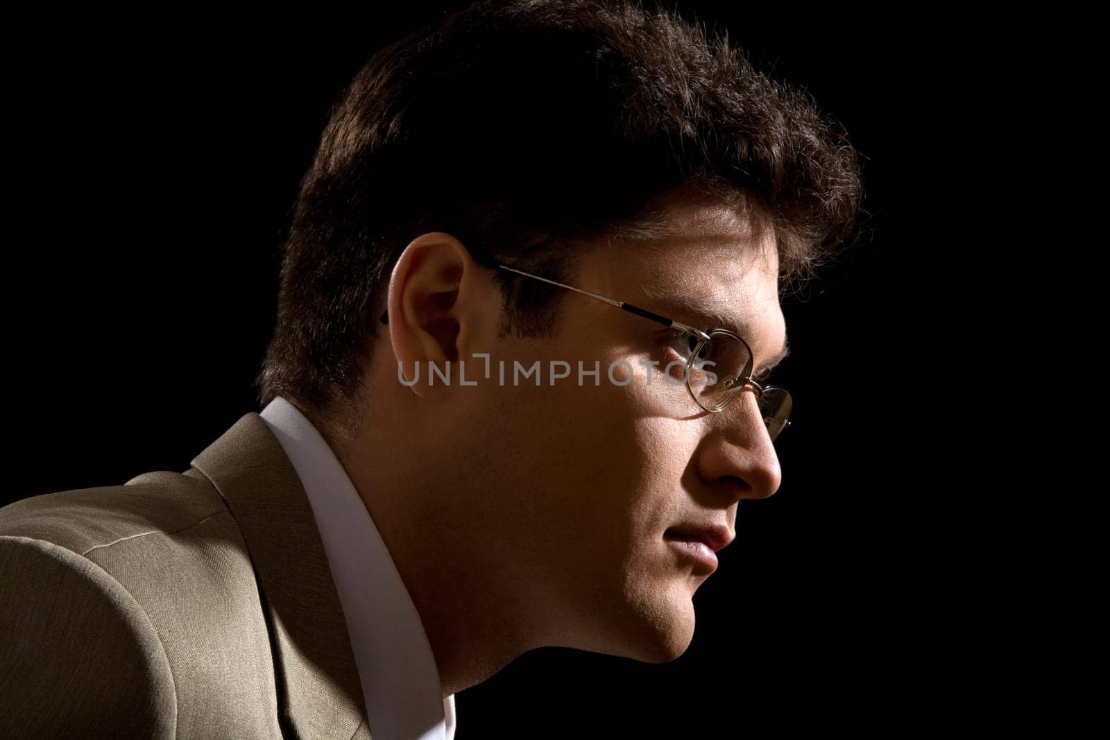 Profile of confident businessman in glasses over black background