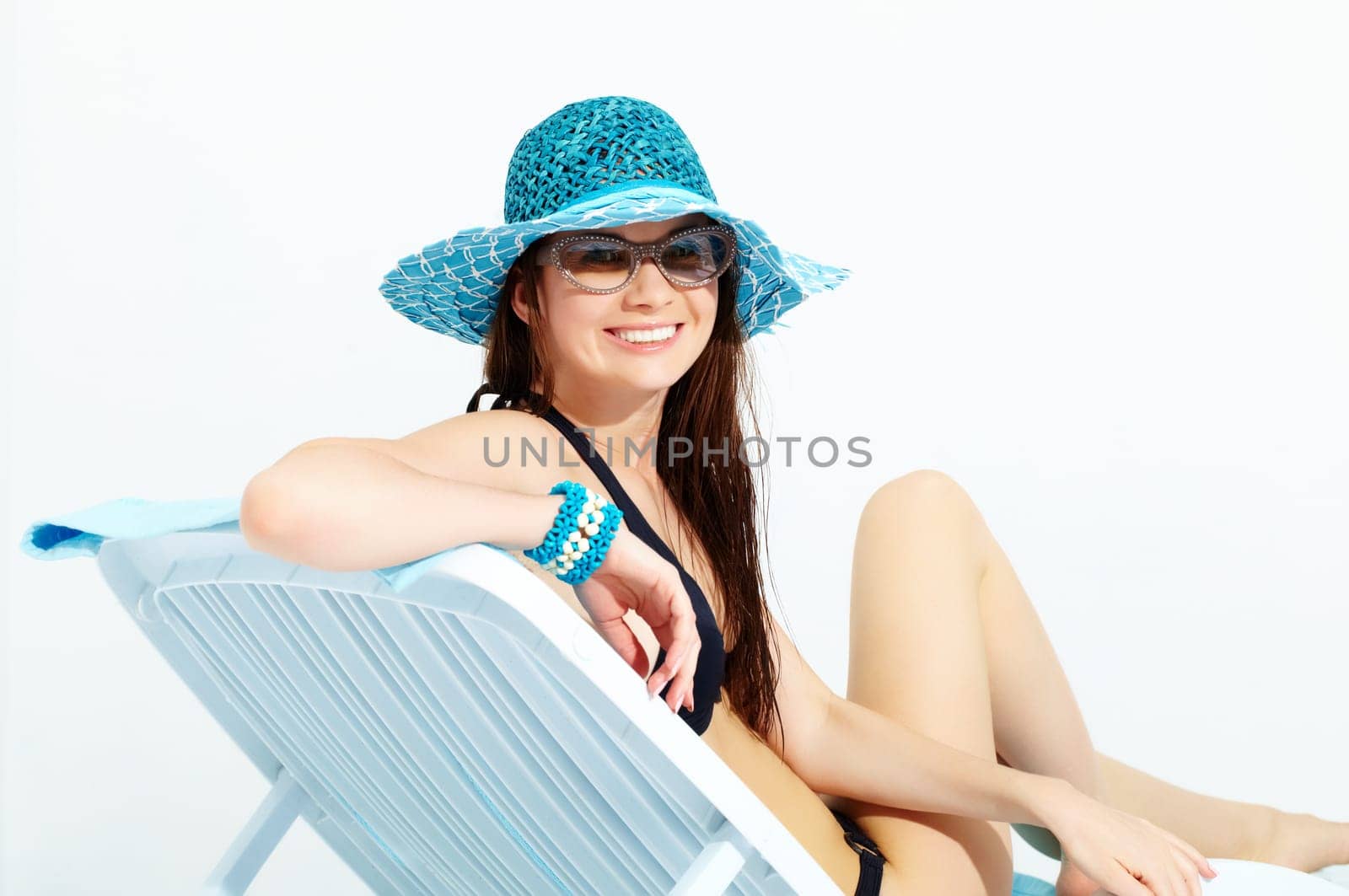 Portrait of a young girl sitting in chaise lounge, looking at camera and smiling