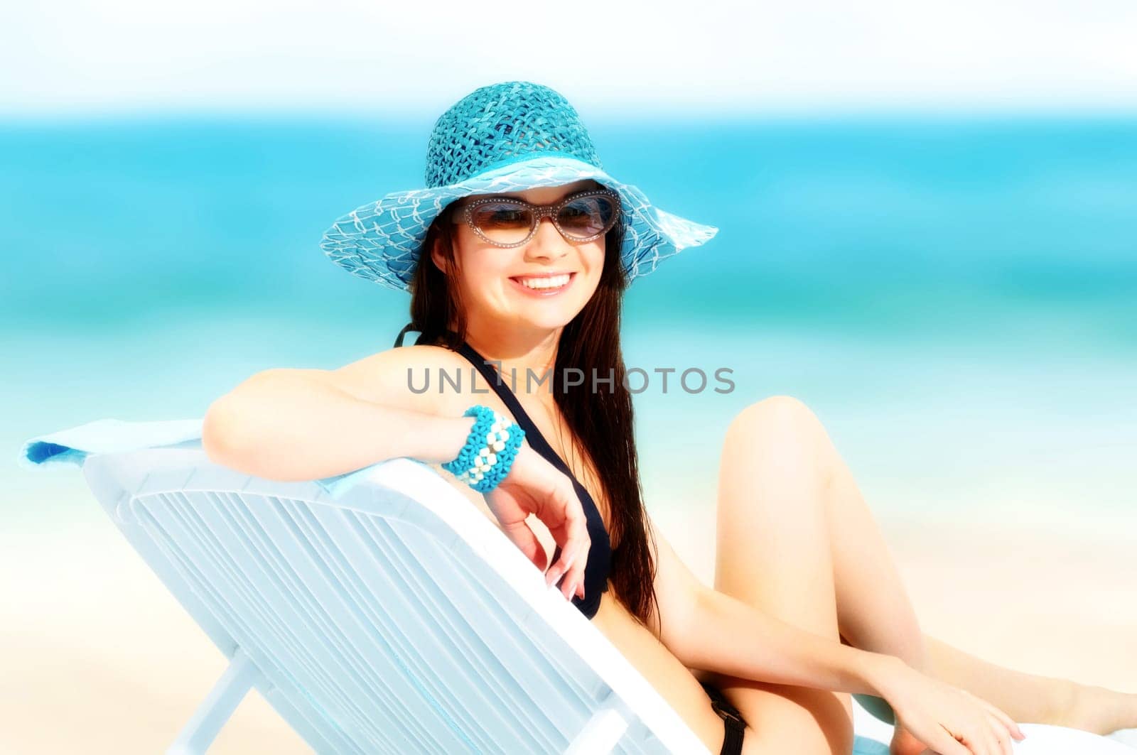 Portrait of a young girl sitting in chaise lounge, looking at camera and smiling