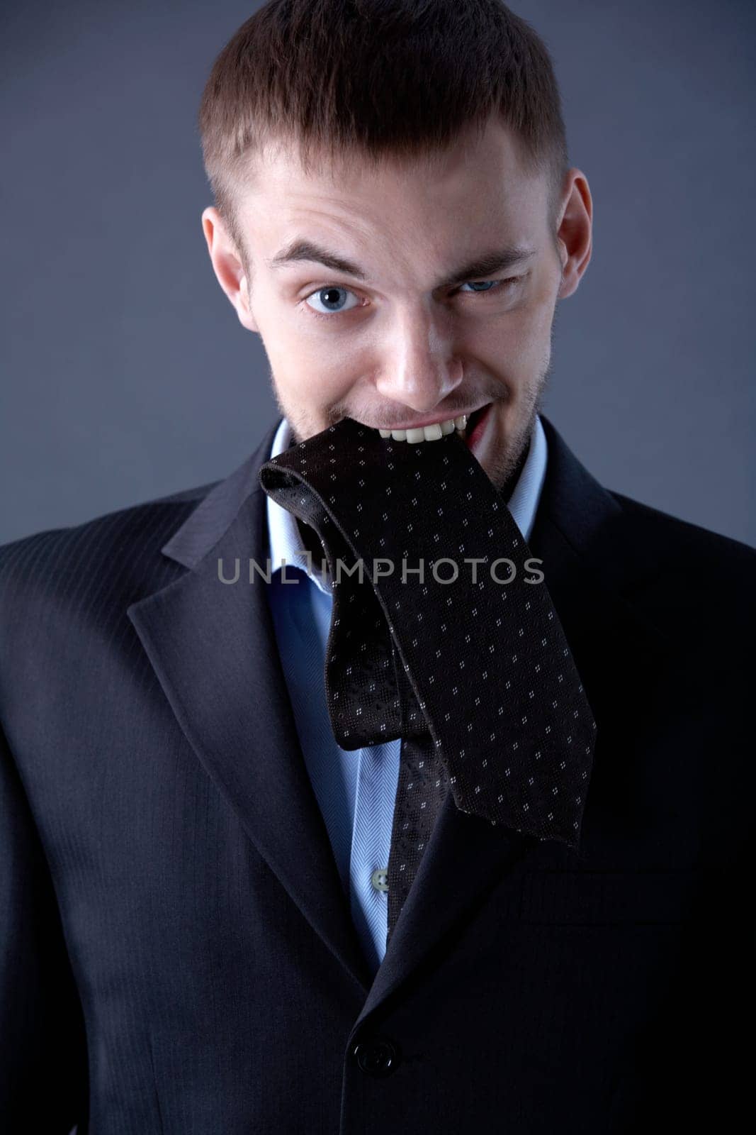 Portrait of odd businessman looking at camera with tie in mouth